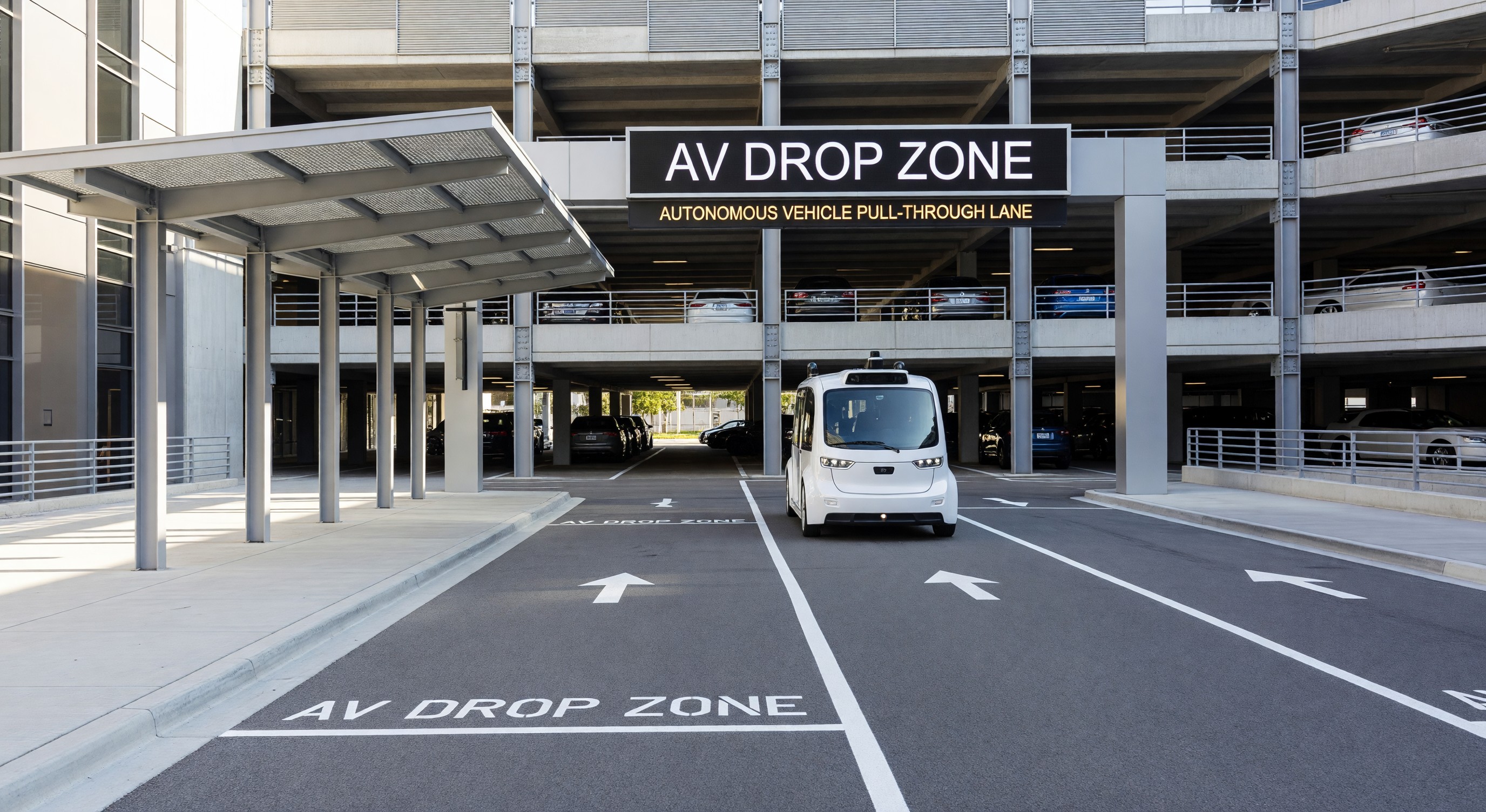 Modern parking facility with AV drop zone and autonomous vehicle pull-through lane at entrance