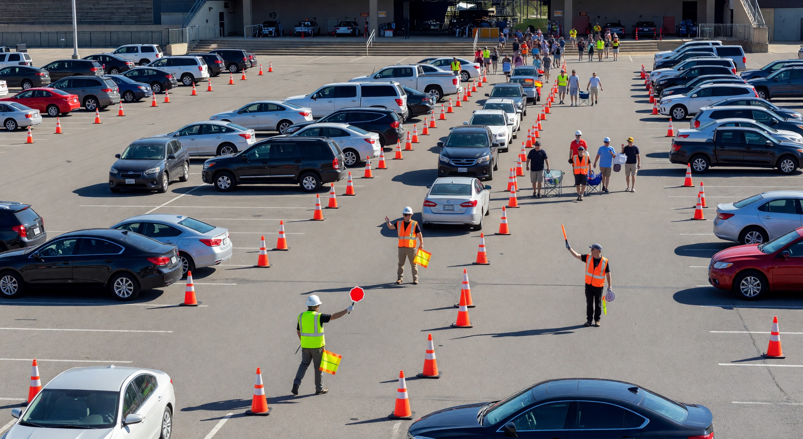 Large outdoor amphitheater parking lots with traffic cones and flaggers directing event attendees to parking areas