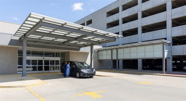 Hospital main entrance with patient drop-off area and adjacent parking garage