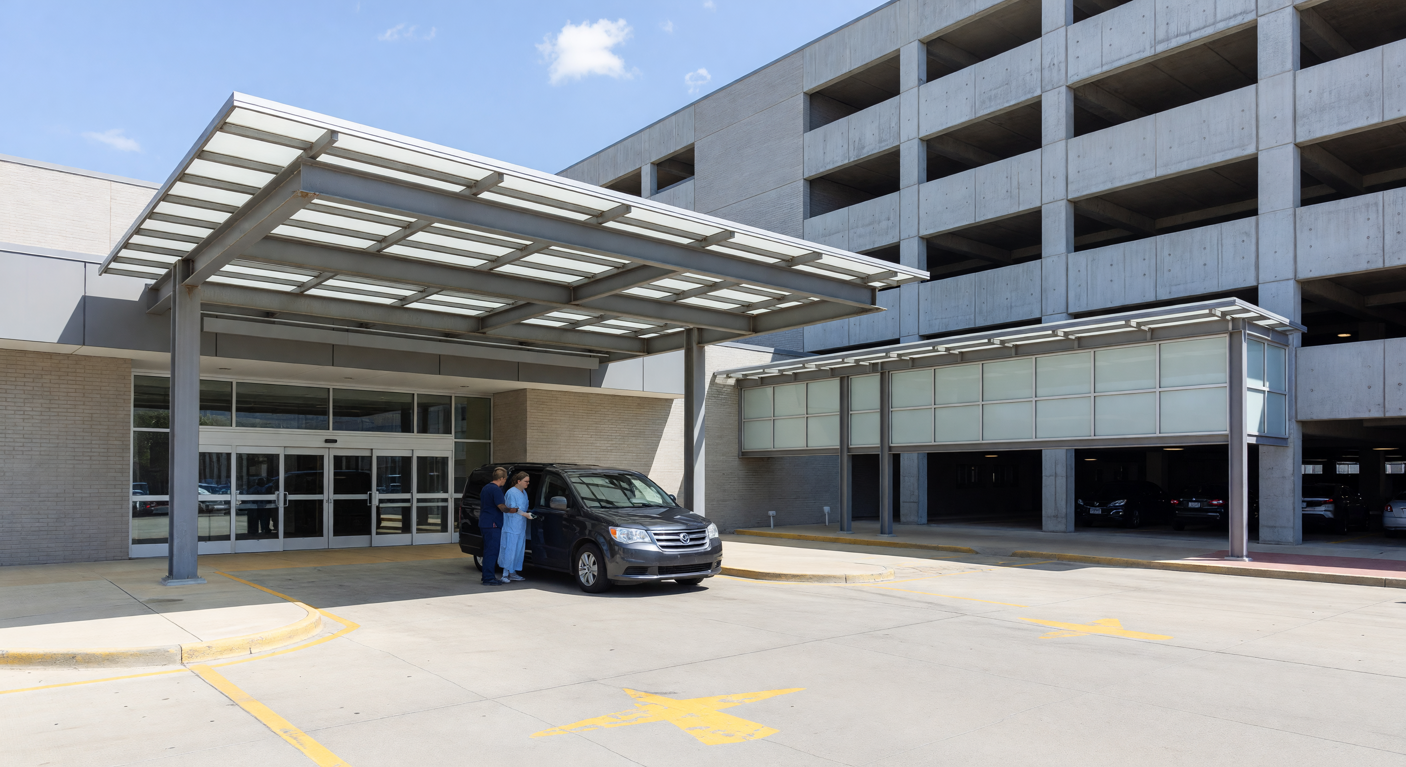 Hospital main entrance with patient drop-off area and adjacent parking garage