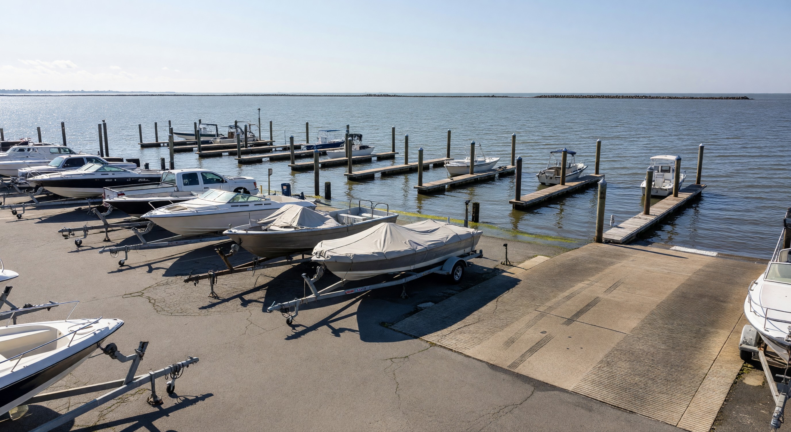 Marina parking lot with boat trailers parked along waterfront with boat slips and launch ramp visible