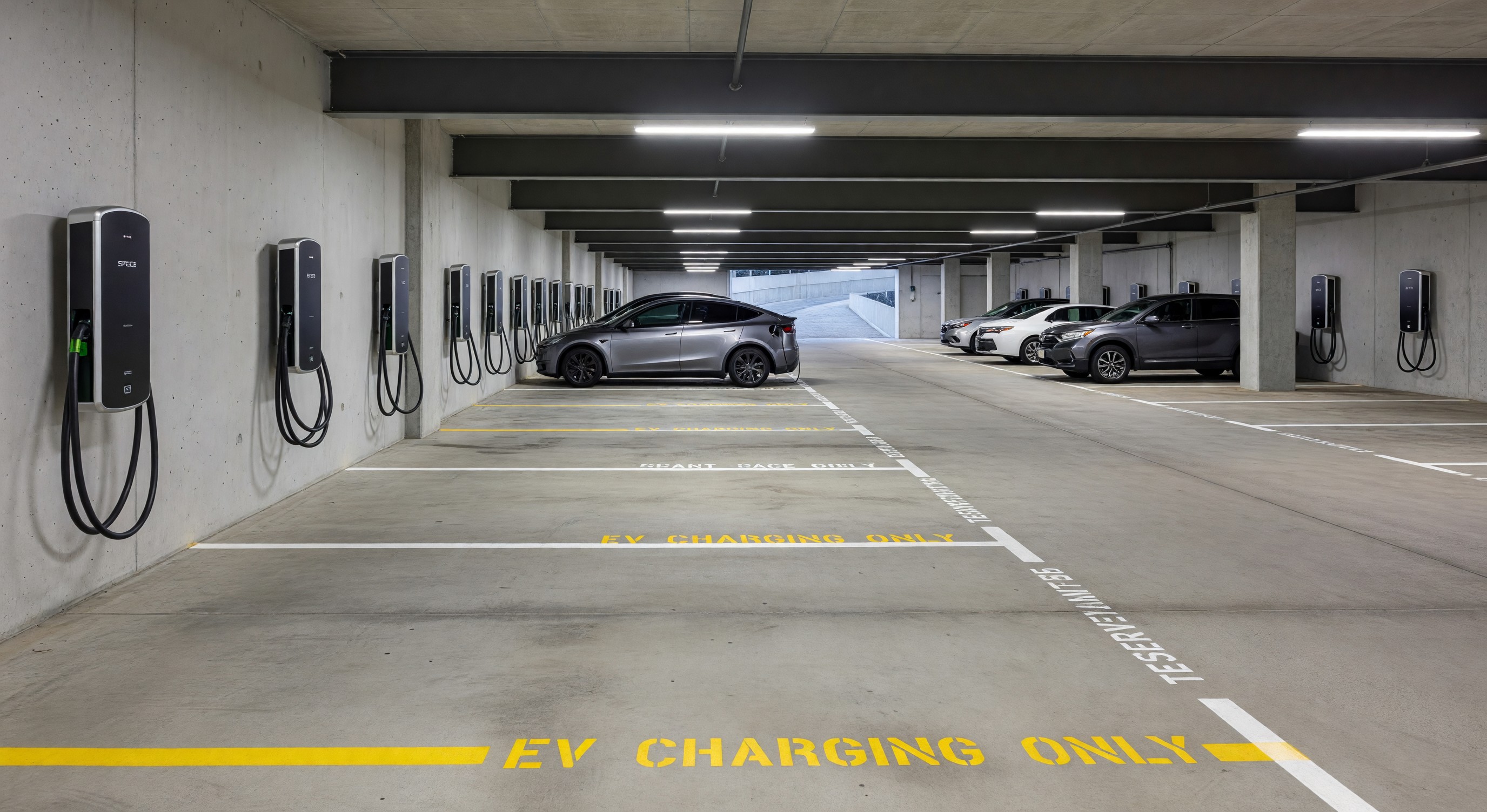 Modern multifamily residential building parking garage with EV charging stations and assigned tenant spaces