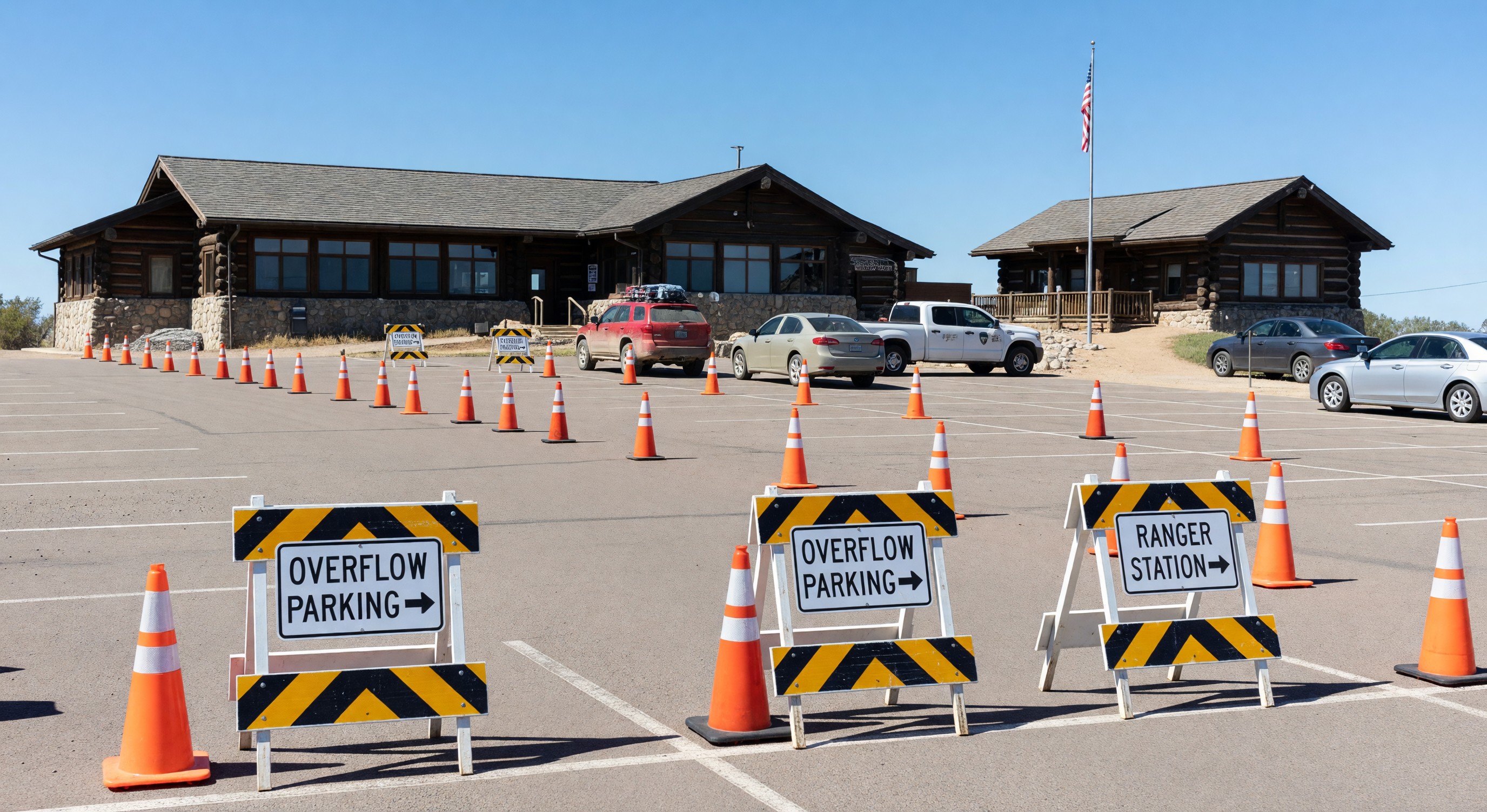National park visitor center parking area with overflow vehicle guidance signs and ranger station visible