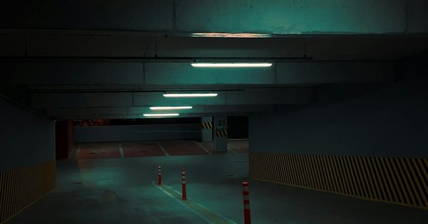 Close-up of ultrasonic parking occupancy sensor mounted on a garage ceiling above an empty parking space