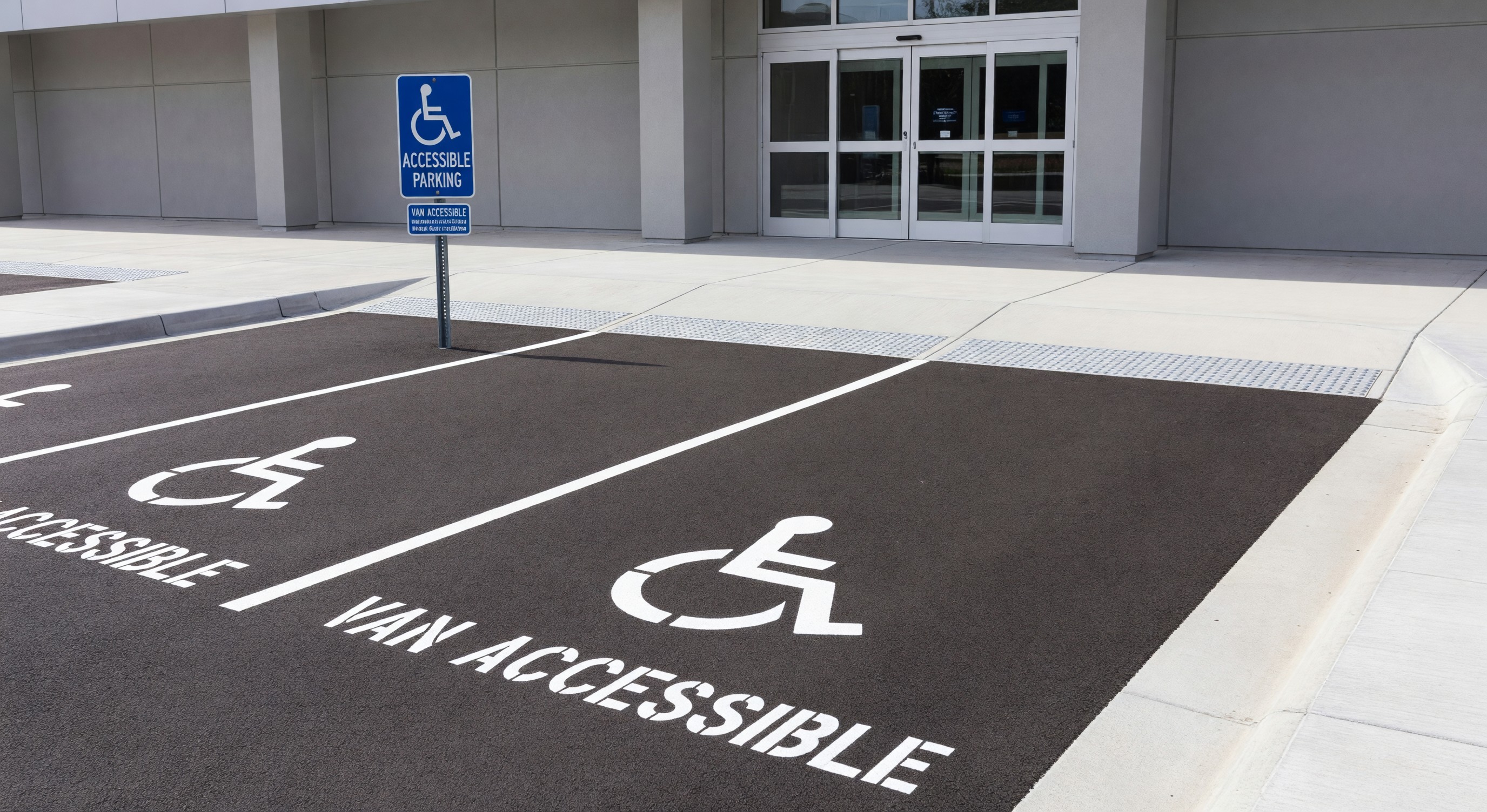 Accessible parking spaces near building entrance with proper signage, curb cuts, and van-accessible space markings