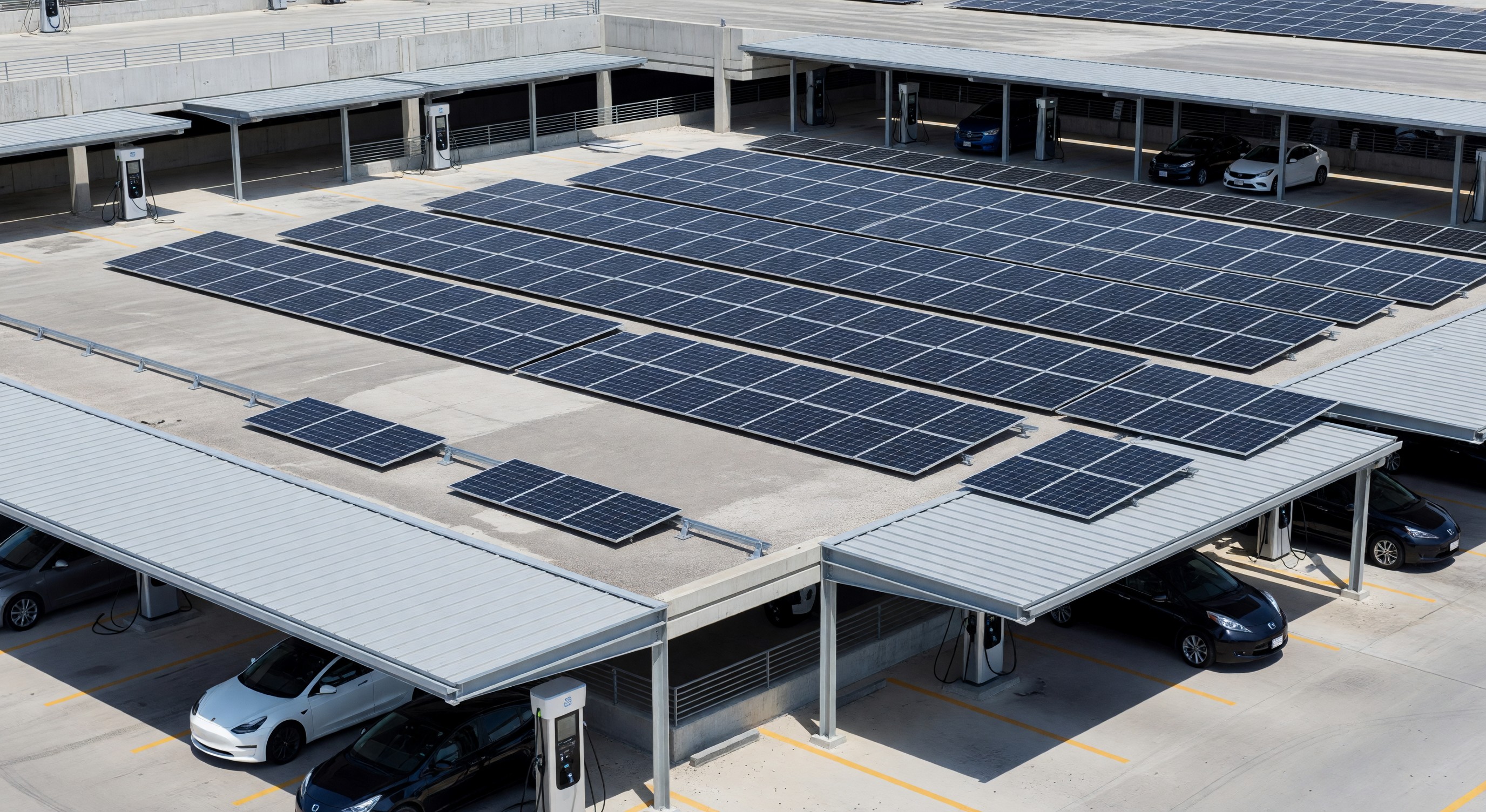 Parking structure rooftop with solar panel array and EV charging stations below carport canopies