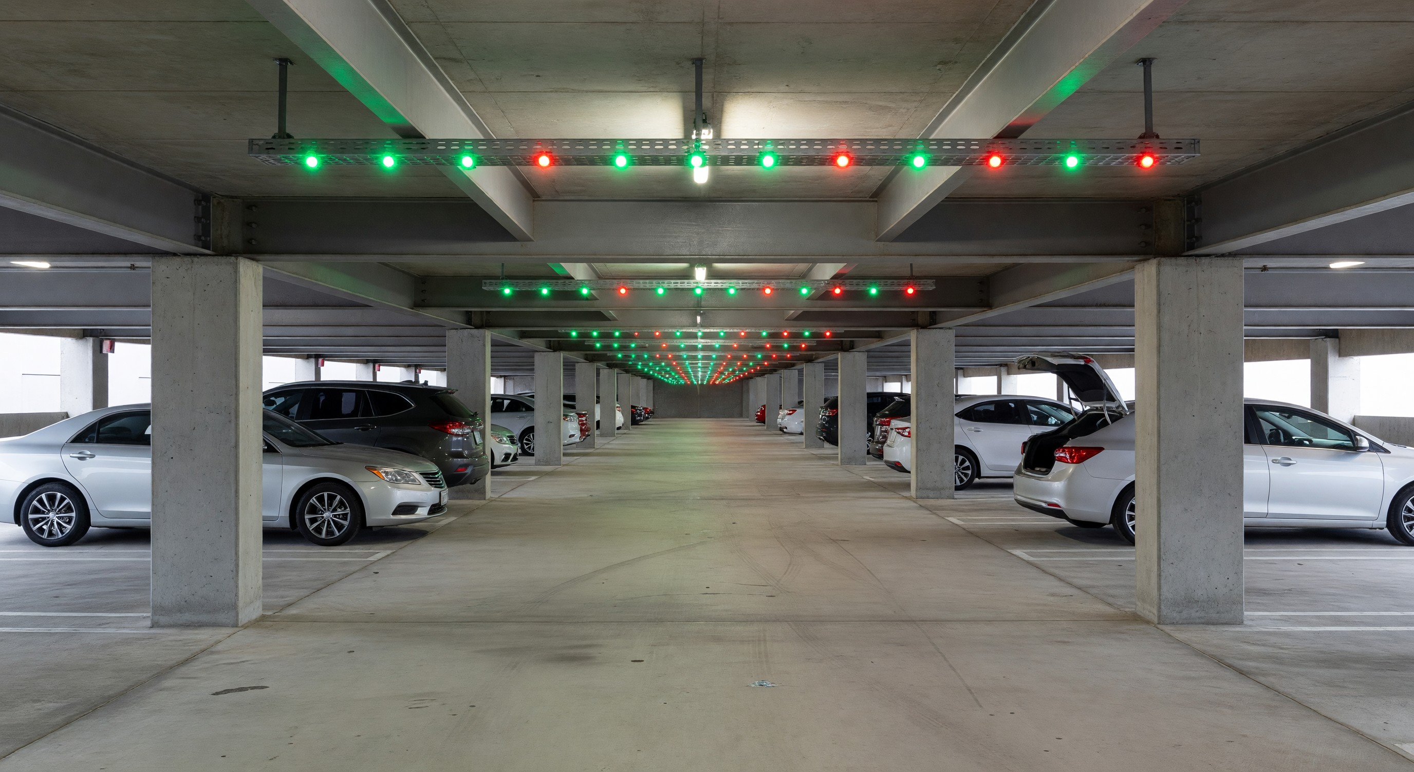 Parking structure with overhead LED space indicators showing green and red lights above individual stalls
