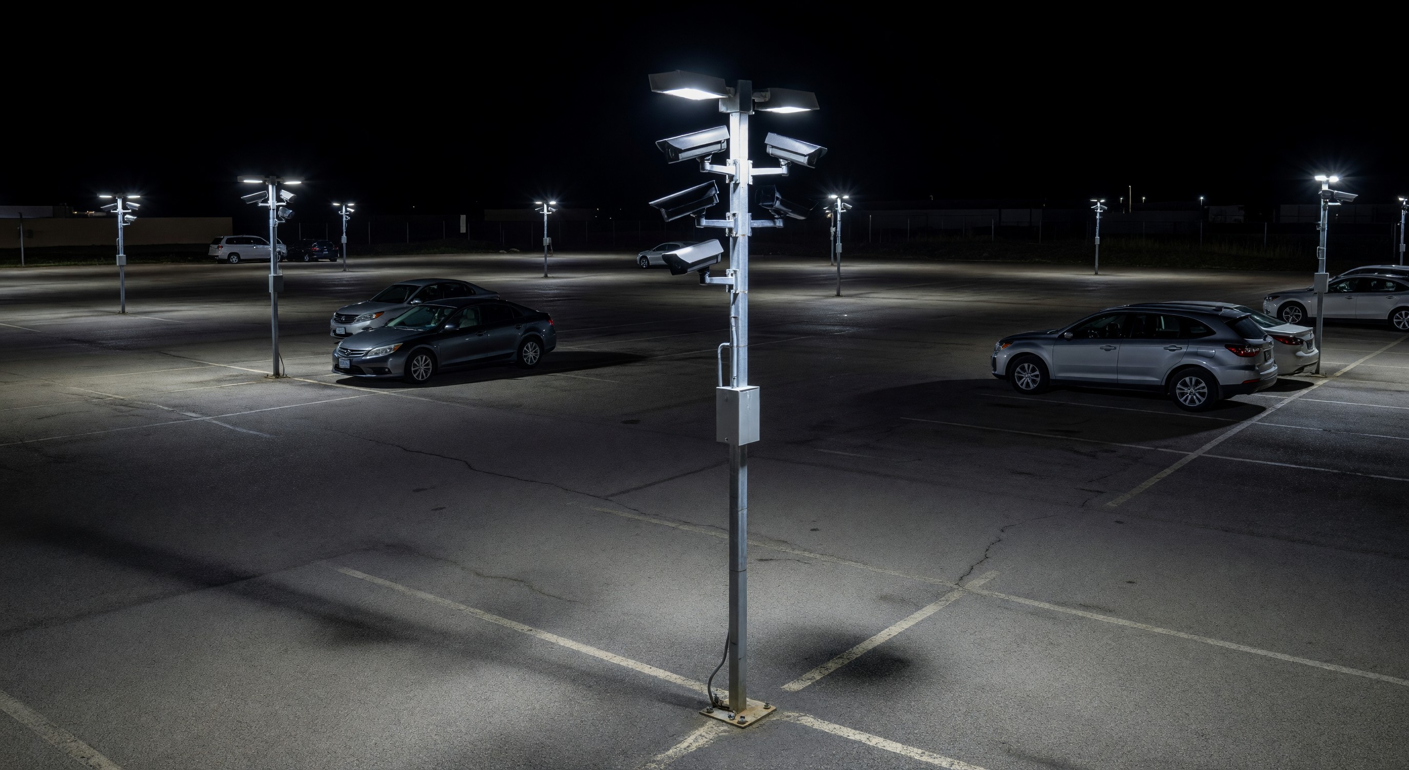 Parking lot at night with security lighting illuminating a CCTV camera installation