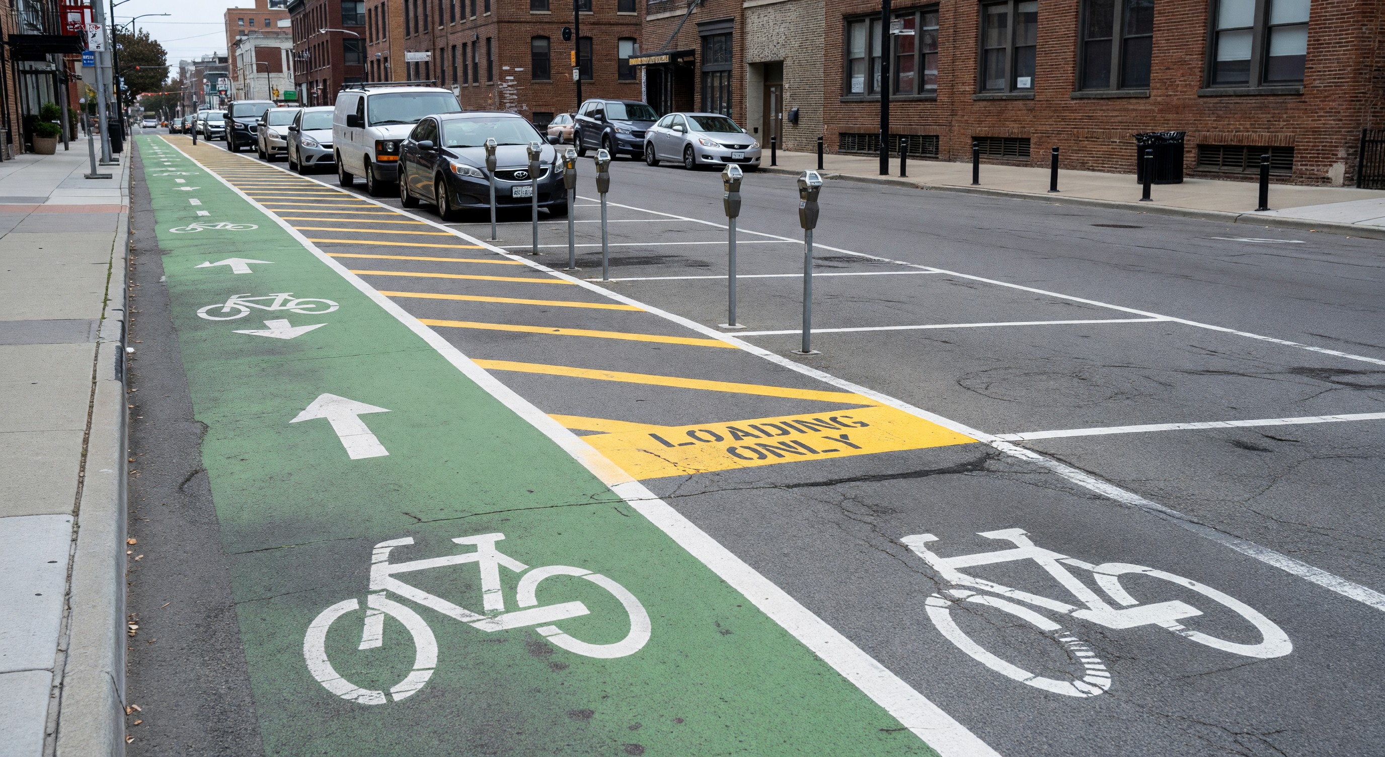 Urban street scene showing mixed curb uses including bike lanes, loading zones, and metered parking