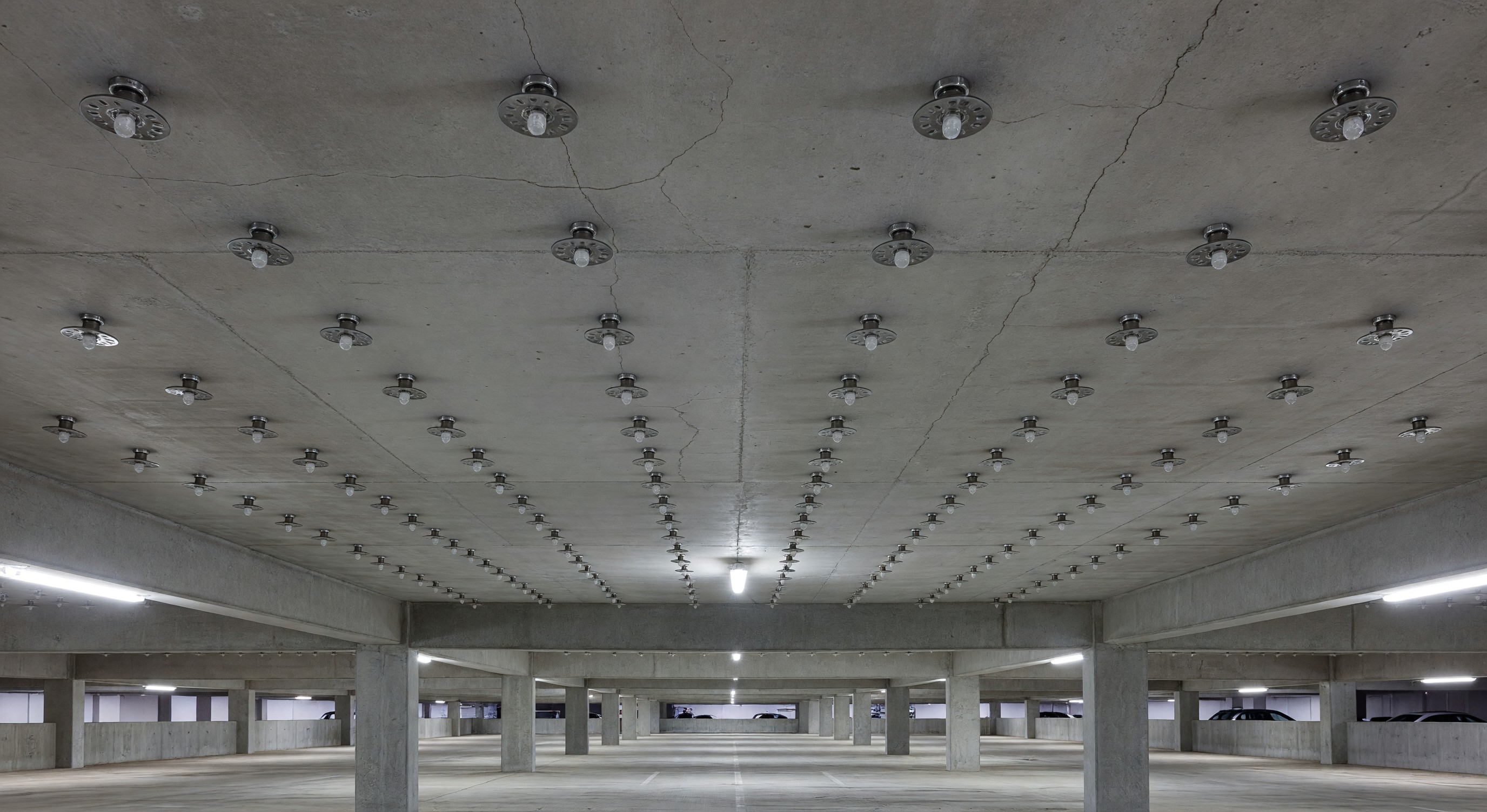 Parking structure interior showing sprinkler heads installed on concrete ceiling