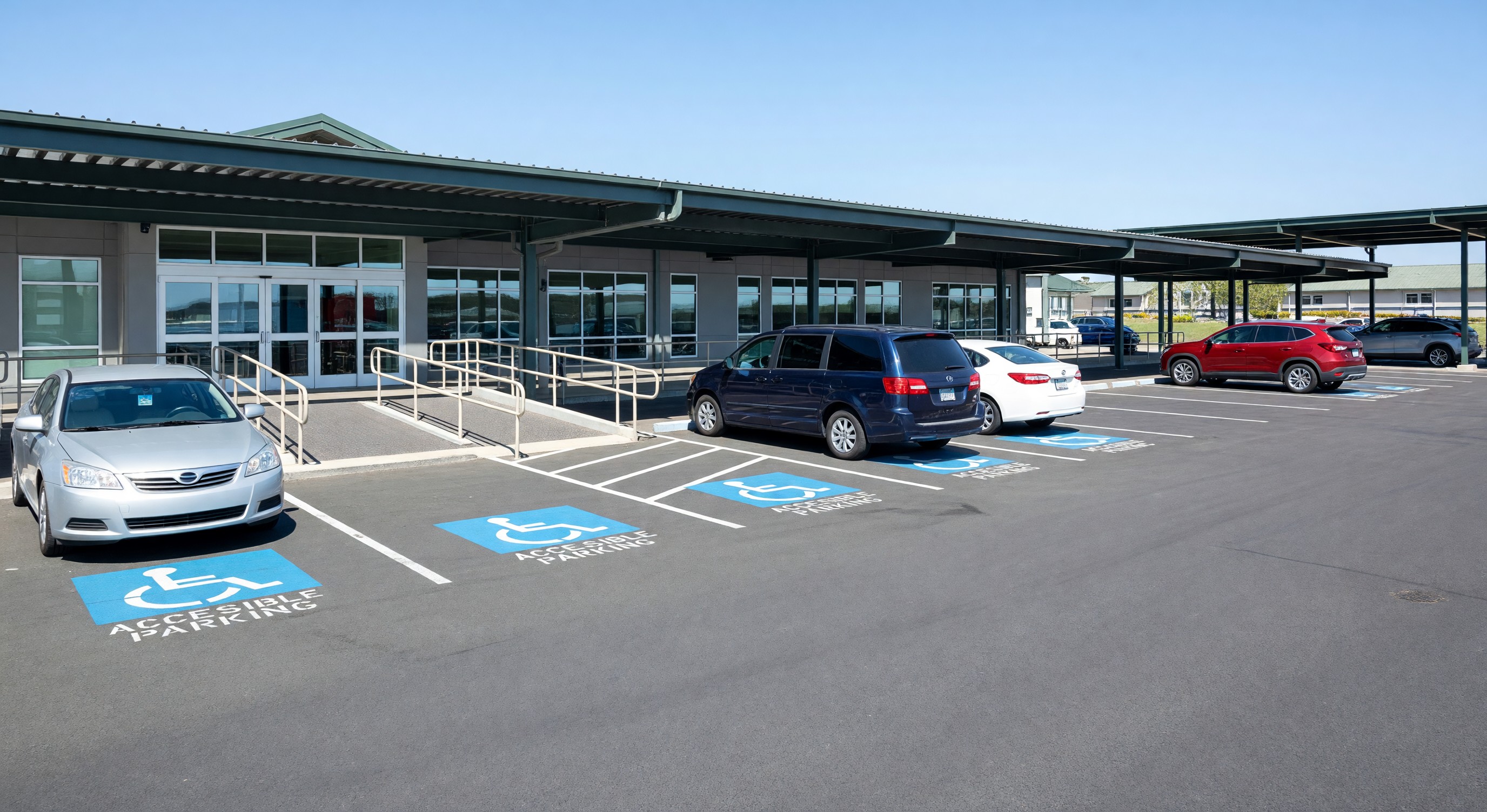 Senior living community parking lot with covered parking, accessible spaces near main entrance and visitor area