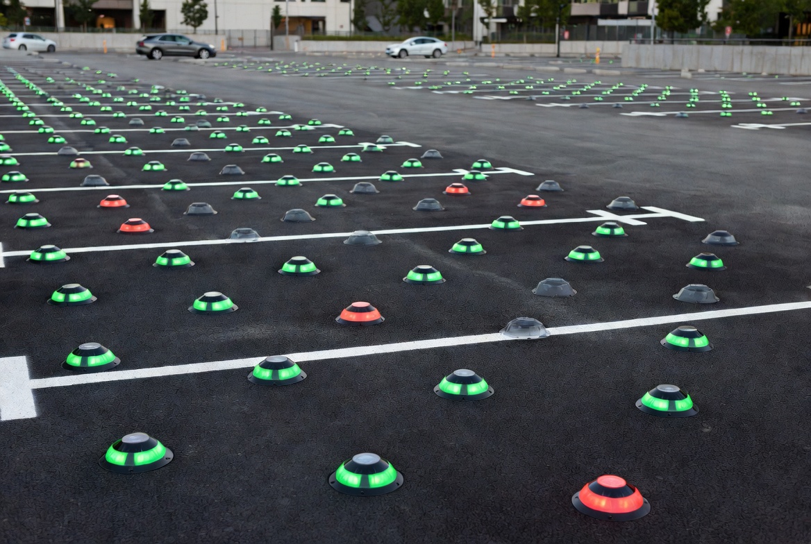 Parking lot with IoT sensors embedded in spaces glowing green and red